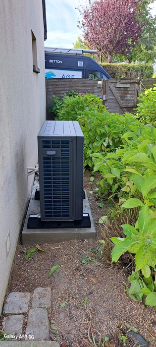 Unité extérieure de pompe à chaleur air/eau installée en extérieur, contre un mur de maison individuelle