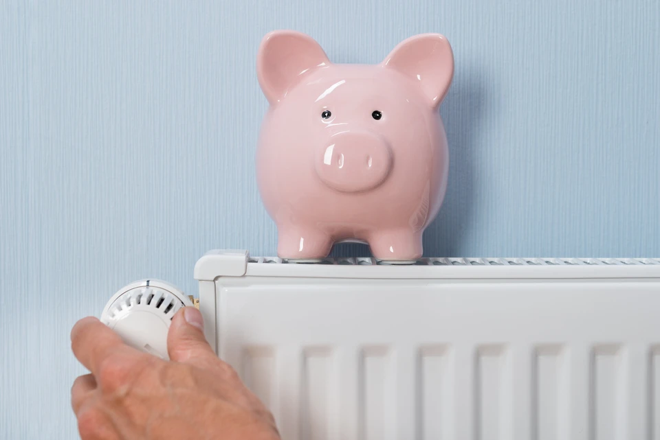 Intérieur domestique avec main masculine ajustant la vanne thermostatique d'un radiateur blanc