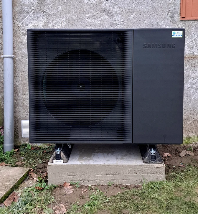 Un technicien en casque jaune et lunettes de sécurité ajuste des vannes sur une installation de plomberie murale