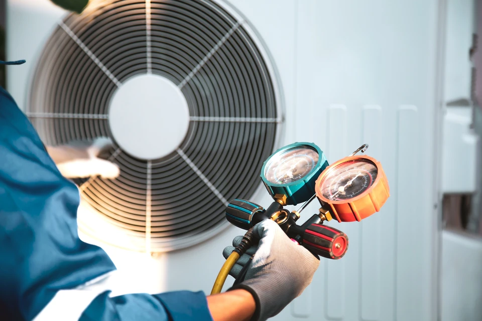 Un technicien d'ACC travaillant sur une pompe à chaleur moderne devant un immeuble