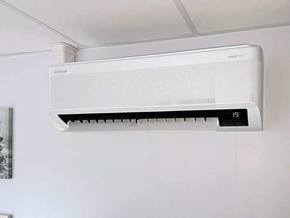 Climatiseur mural réversible Samsung WindFree™ installé en hauteur dans un espace intérieur blanc